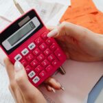 două persoane compară documente financiare și un calculator