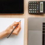 Persoană calculând gradul de îndatorare pe laptop înainte de a aplica pentru credit
