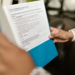 Persoană analizând documente bancare și calcule de credit acasă la birou