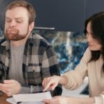 Bărbat calculează rate credit și documente de refinanțare acasă