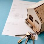 Cuplu semnând documente pentru credit ipotecar cu chei de casă pe masă