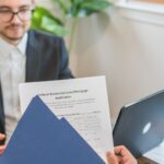 Bărbat analizează documente de credit ipotecar la birou, calculator și extrase bancare