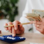 Persoană calculează rate și buget pentru un credit de nevoi personale acasă