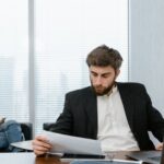 Analist bancar verifică dosarul de refinanțare credit pe calculator