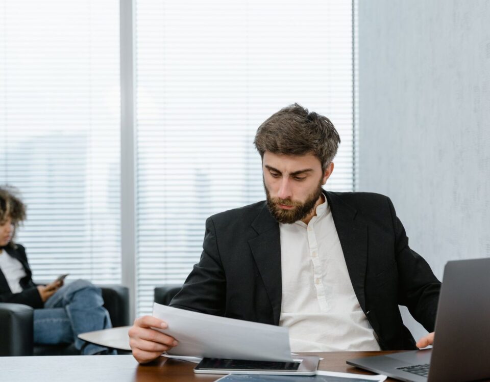 Analist bancar verifică dosarul de refinanțare credit pe calculator