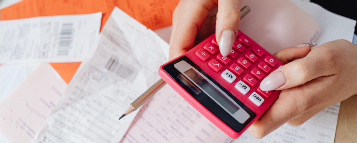 Persoană calculând ratele la credit și facturile pe o masă de birou