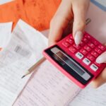 Persoană calculând ratele la credit și facturile pe o masă de birou