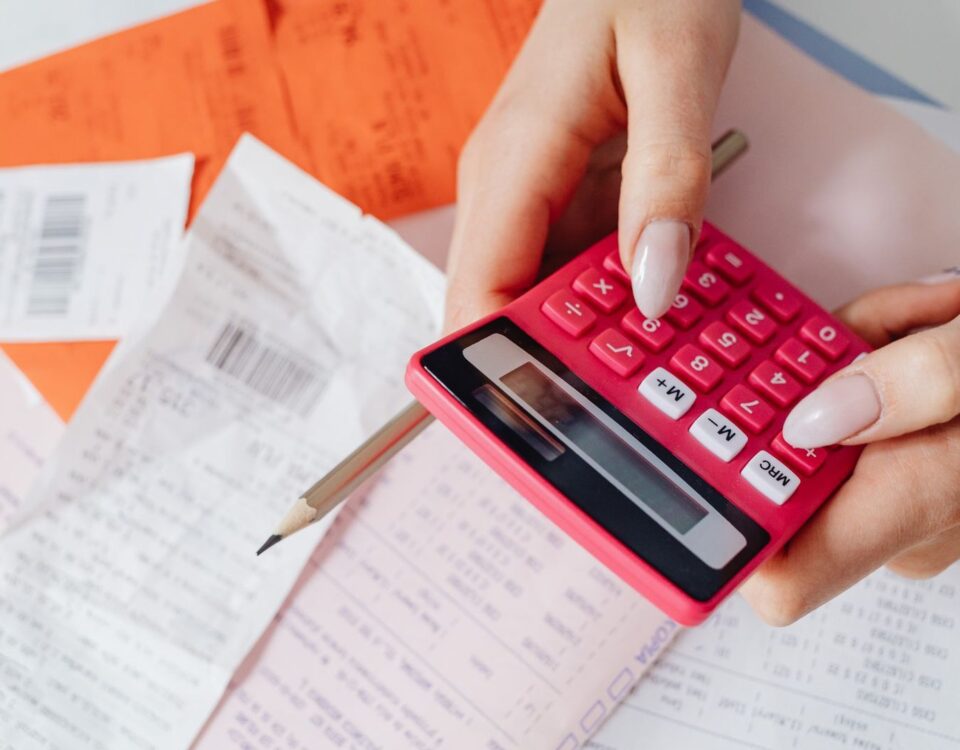 Persoană calculând ratele la credit și facturile pe o masă de birou